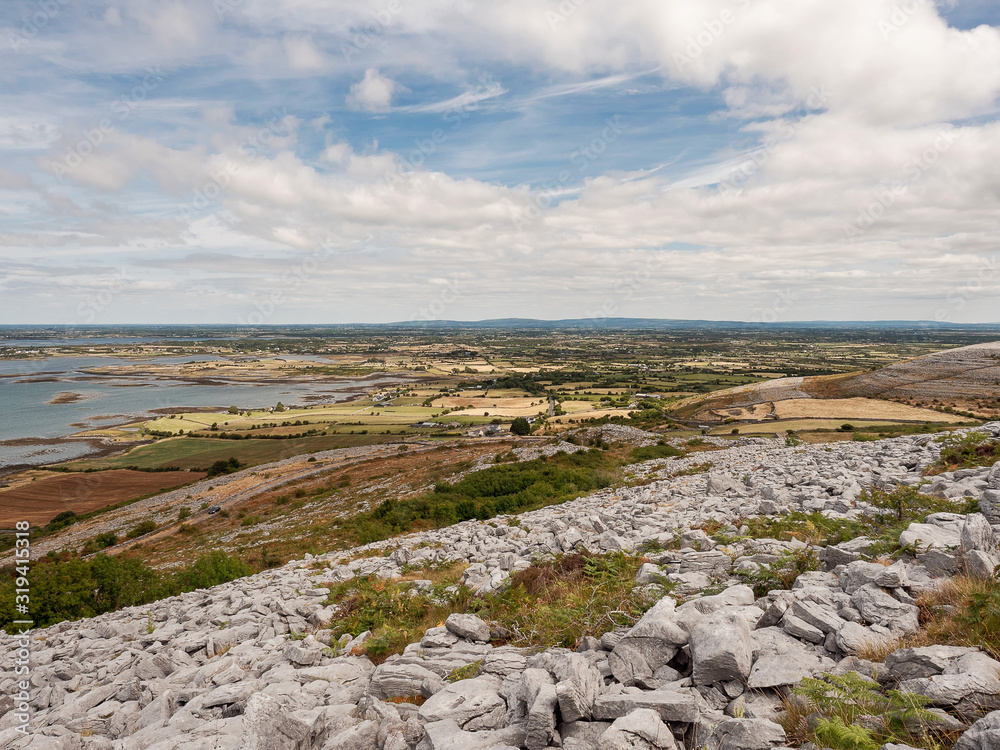 View on Galway bay from a mountain in Burren, Warm summer day Cloudy sky, Nobody. Rough mountain terrain in foreground.