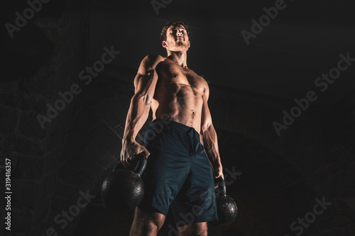 Fit muscular bodybuilder man posing on dark background