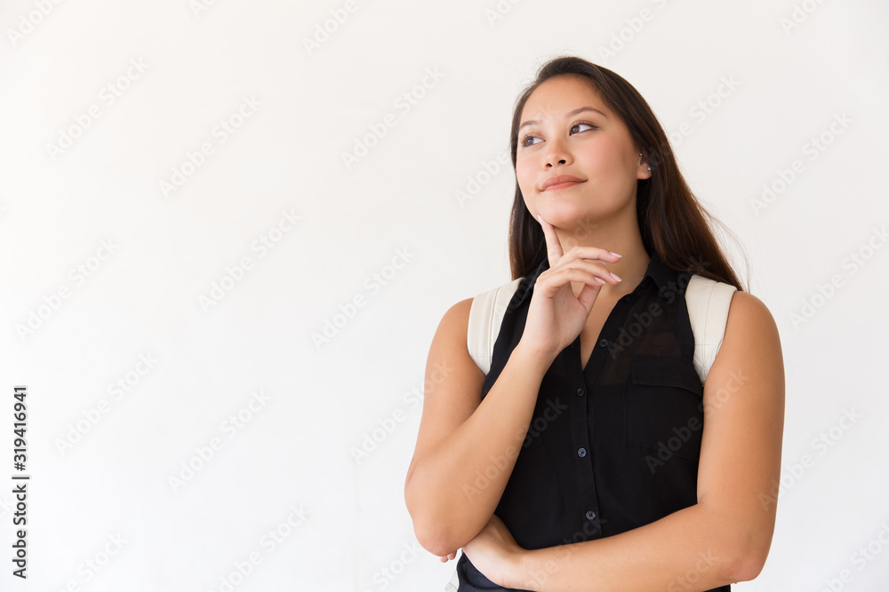 Pensive young woman with backpack looking aside. Portrait of thoughtful young female college student standing with finger on chin and looking away on white background. Education concept Pensive young woman with backpack looking aside. Portrait of thoughtful young female college student standing with finger on chin and looking away on white background. Education concept