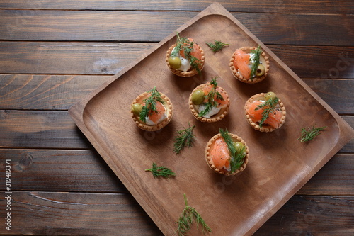 Tartalets with fresh salmon, philadelphia cream cheese, olives on wooden background