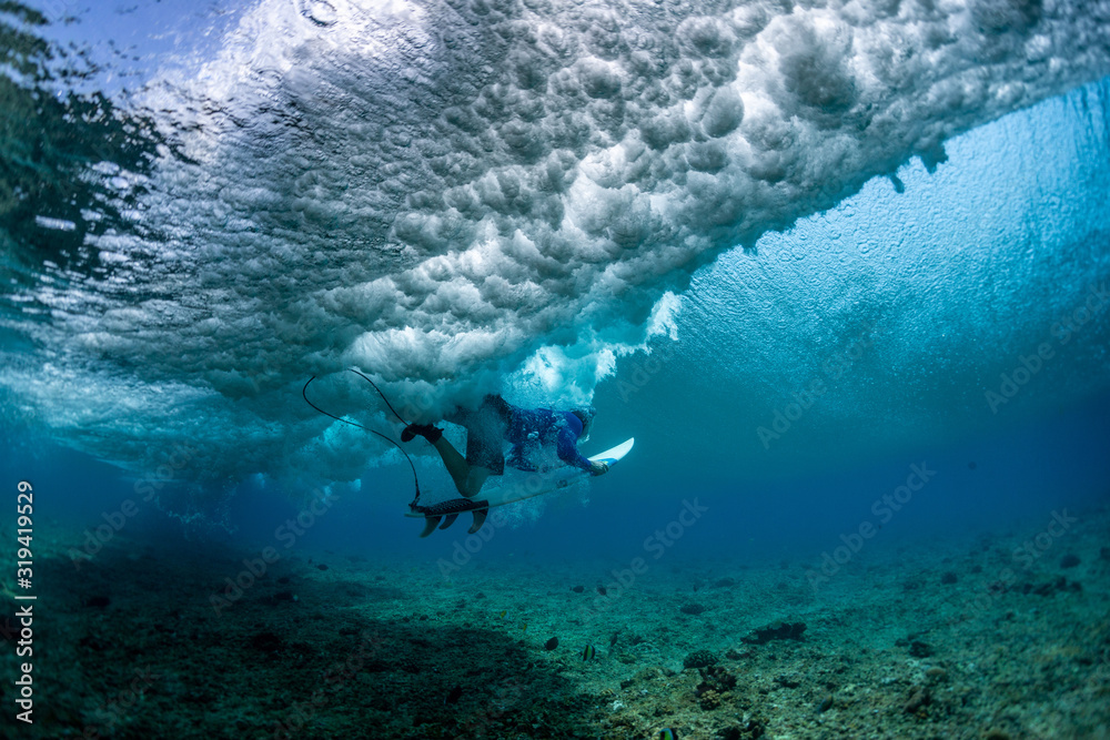 Fototapeta premium Surfer dives under the wave