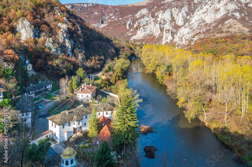 Beautiful panorama of the Iskar River Gorge in the autumn and the Cherepish Monastery "God's Mother Assumption", Bulgaria. River valley, colorful autumn forest, orthodox monastery and rocky mountain 