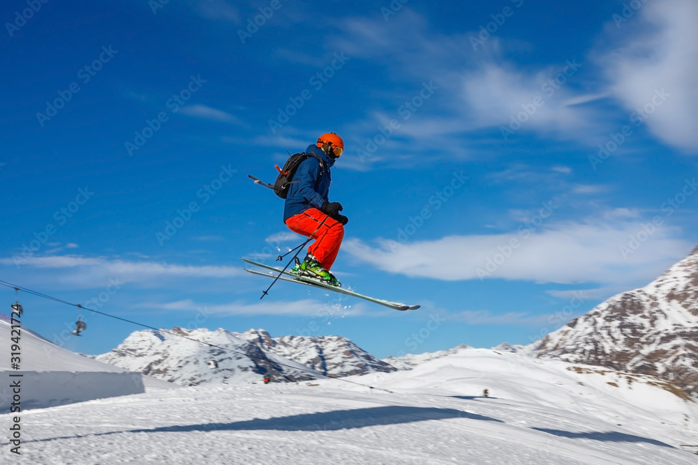 Male skier jumps in snow park against the blue sky