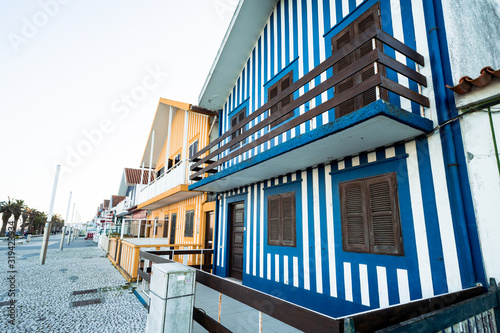 Colorful striped fishermen beach houses (Palheiros) with yellow, red, blue and green stripes in Costa Nova Portugal, a resort town near Aveiro © MelissaMN