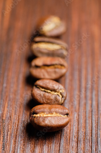 Laid out in a row of coffee beans on a burnt wooden background. Vertical.