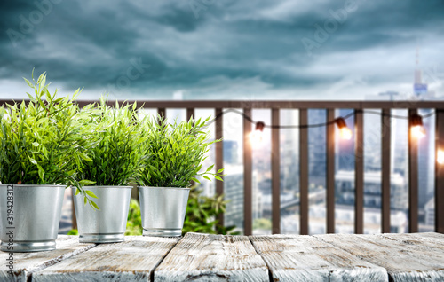 Fototapeta Naklejka Na Ścianę i Meble -  White wooden table of free space and small green plants. City landscape with dark sky and copy space for your decoration. 