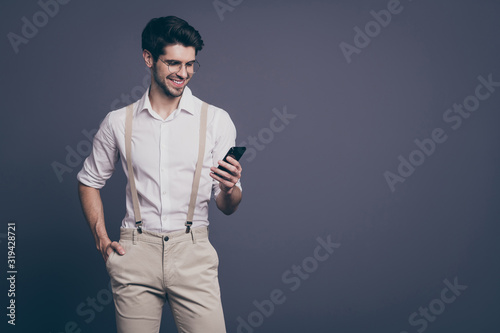 Photo of successful business man good mood holding telephone hands read work email dressed formalwear shirt suspenders trousers specs isolated grey color background