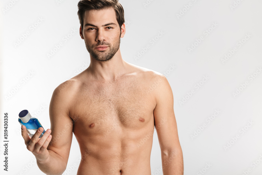Fototapeta premium Photo of confident half-naked man looking at camera and showing perfume