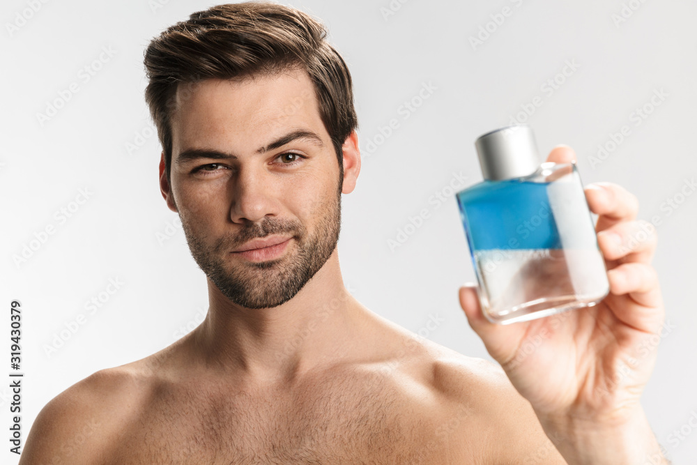 Photo of sassy half-naked man posing and showing perfume Photo of sassy half-naked man posing and showing perfume