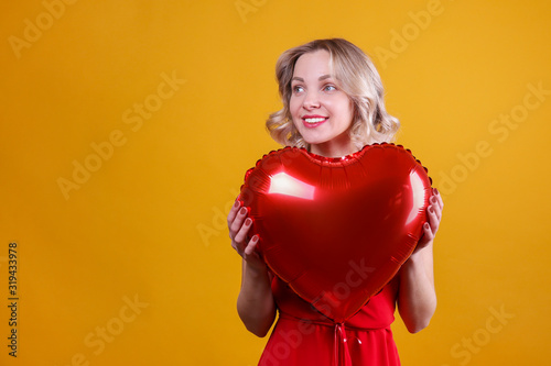 Portrait of young blonde woman posing with helium inflated air balloon. Happy valentine's day concept. Happy female with curled hair over colorful background. Close up, copy space for text.