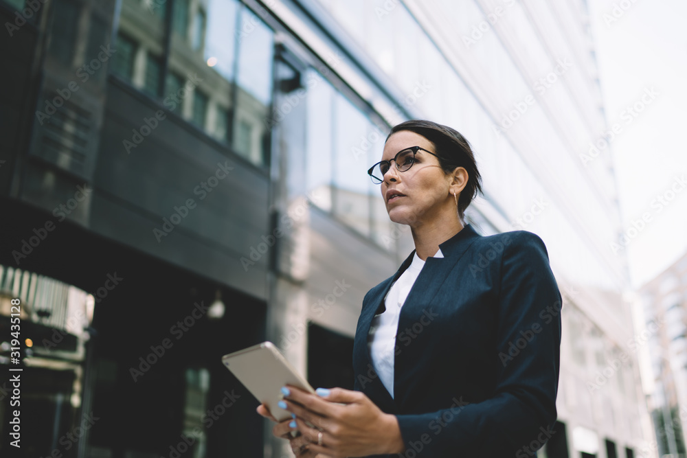 Concentrated businesswoman walking with tablet in street Concentrated businesswoman walking with tablet in street