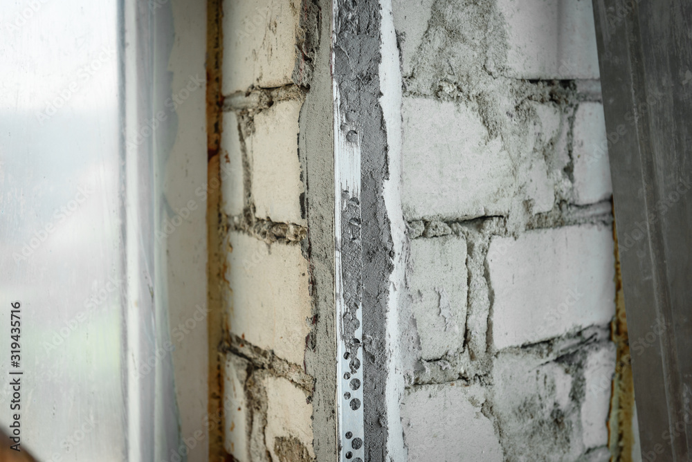 The plasterer repairs the corners of the window with a spatula and plaster. Construction finishing works.