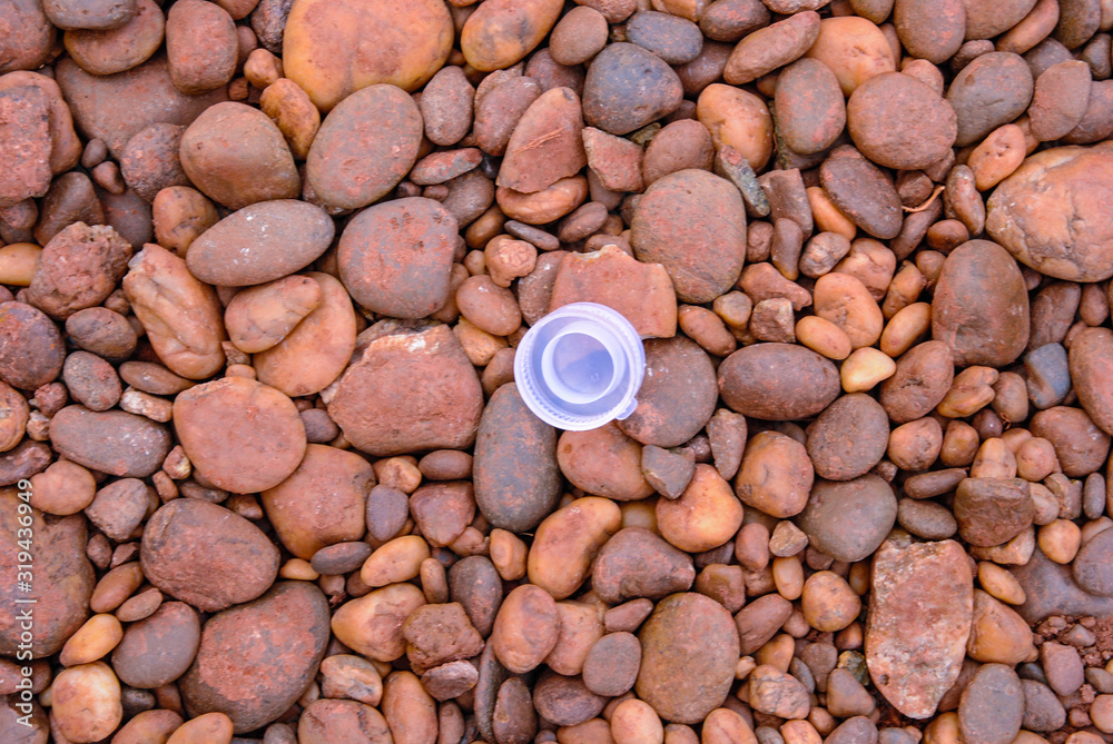 Clear plastic bottle cap on a brown round pebble. Clear plastic bottle cap on a brown round pebble.