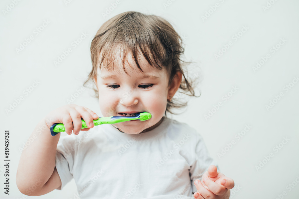 Little girl brushes her teeth with a toothbrush on a light background Little girl brushes her teeth with a toothbrush on a light background