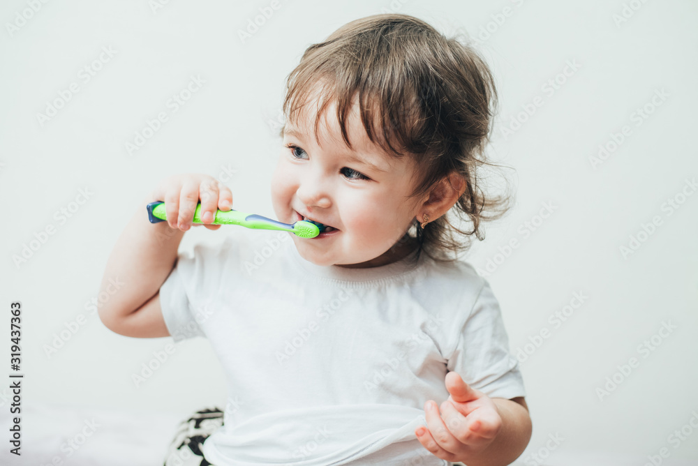 Little girl brushes her teeth with a toothbrush on a light background Little girl brushes her teeth with a toothbrush on a light background