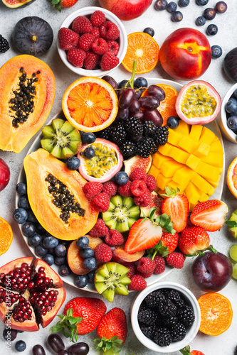 Fototapeta Naklejka Na Ścianę i Meble -  Healthy raw rainbow fruit platter mango papaya strawberries oranges passion fruits berries on oval serving plate on light concrete background, top view, selective focus