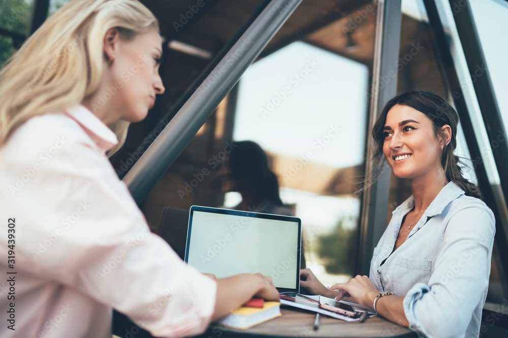 Female colleagues using laptop working outside of cafe