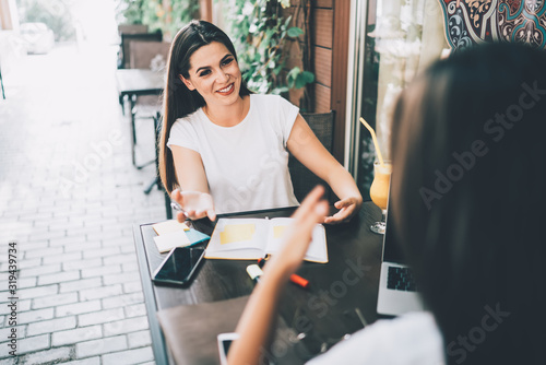 Fotografie Positive ladies discussing work at pavement cafe