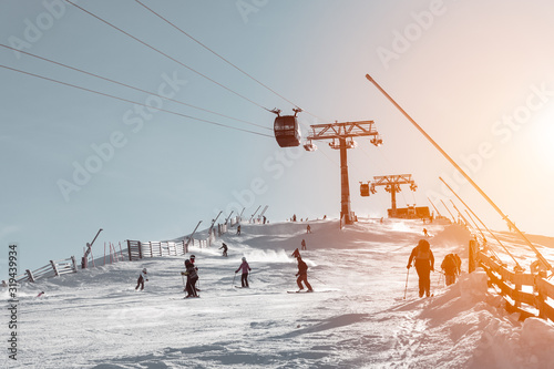 Skiers riding down the ski slope under the cable car