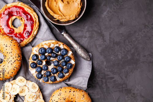 Variety of bagels with different toppings and natural paleo nut peanut cashew creamy butter on dark gray background. Healthy breakfast brunch concept. Top view,flat lay,copy space,horizontal orientati photo