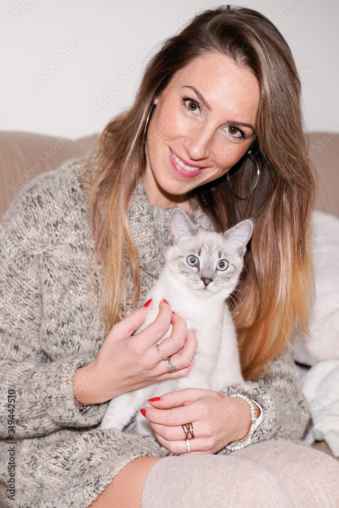 portrait of beautiful young woman holding siamese cat on home sofa portrait of beautiful young woman holding siamese cat on home sofa