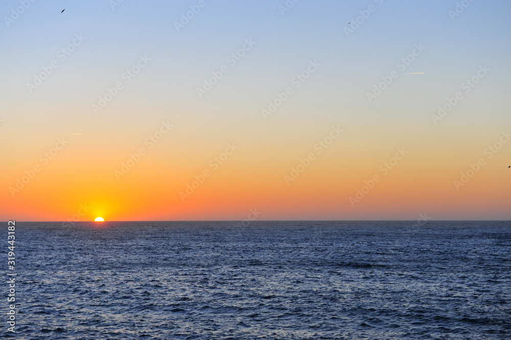 Scenic view of the sun going down with the deep blue ocean