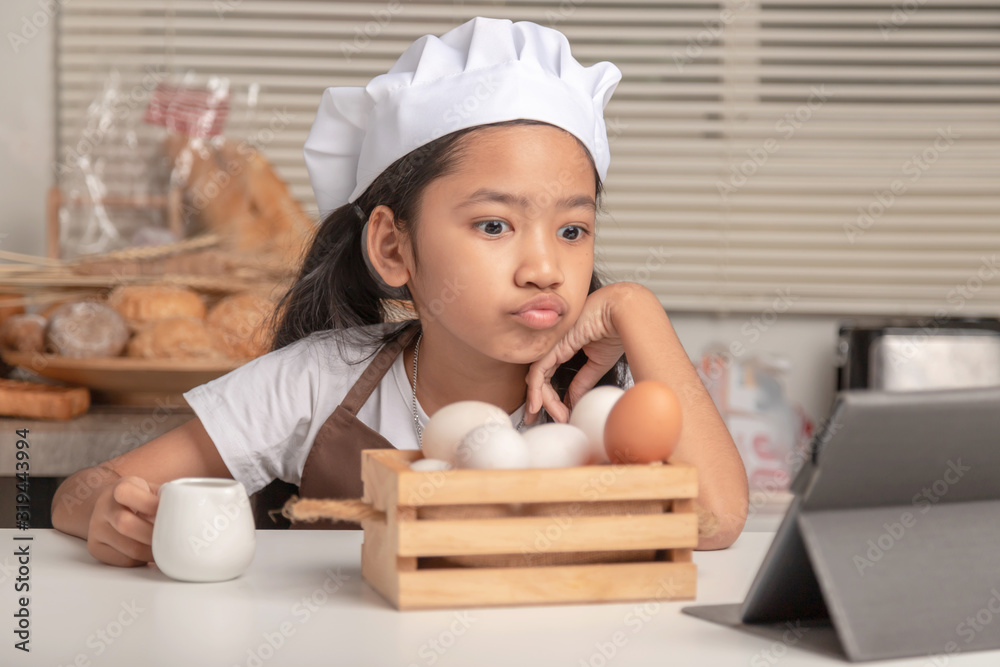 An Asian girl is watching how to make a bakery from a laptop An Asian girl is watching how to make a bakery from a laptop