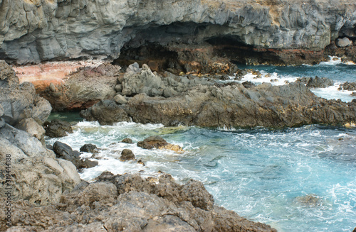 East coast of Tenerife. Rocky grotto and azure sea. Waves constantly hitting the rocky shore.