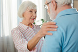 Selective focus of smiling senior woman embracing husband at home