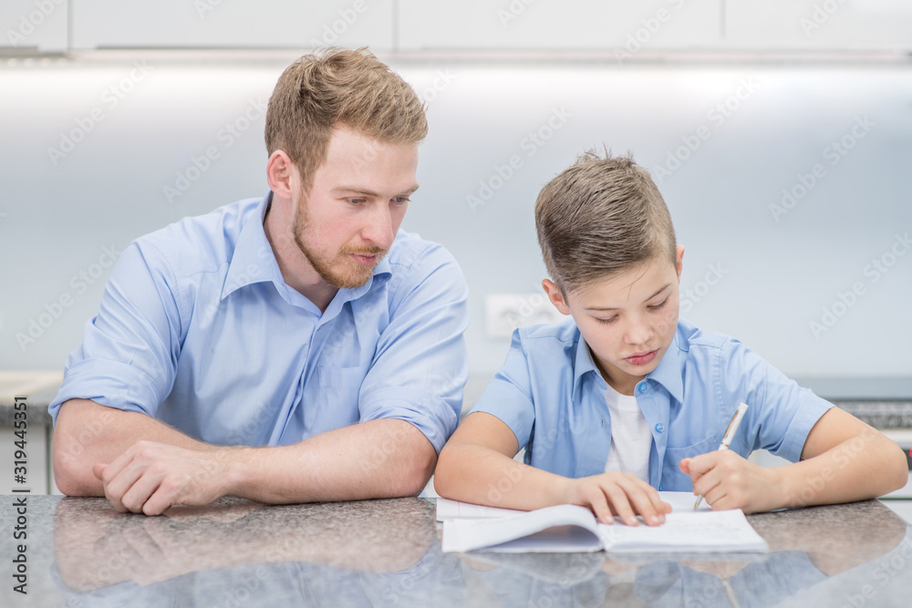 Fototapeta premium Father helps his son doing homework at home