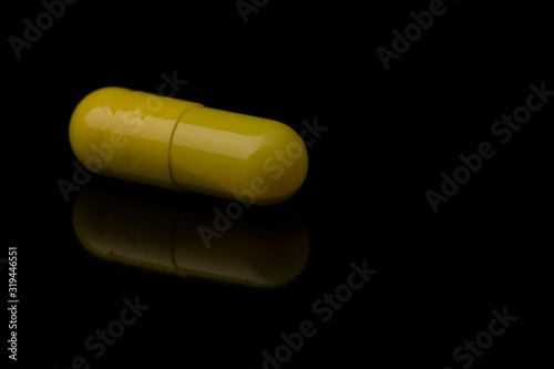 Yellow Pill On Black Background, close up