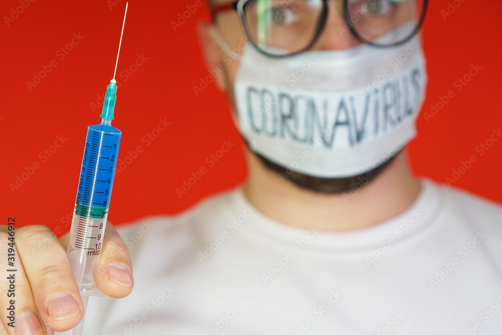 An injection of blue in the syringe in the foreground, in the background a blurred doctor in glasses and a mask. The concept of the virus, coronovirus. Virus vaccine An injection of blue in the syringe in the foreground, in the background a blurred doctor in glasses and a mask. The concept of the virus, coronovirus. Virus vaccine