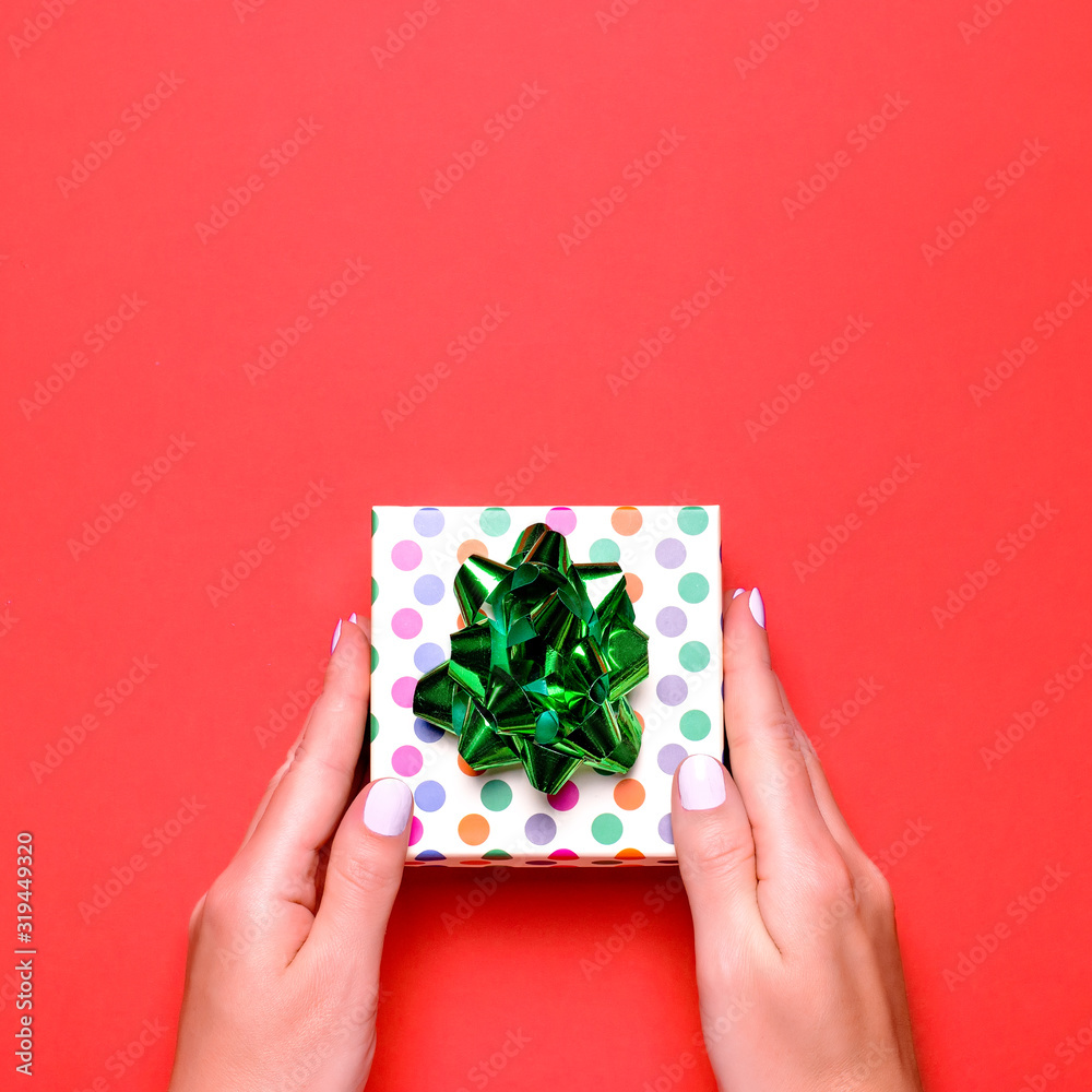 Woman presenting gift with green ribbon on lush lava color background, copyspace. Valentine's Day or Mother's Day greeting card in trendy colors, top view Woman presenting gift with green ribbon on lush lava color background, copyspace. Valentine's Day or Mother's Day greeting card in trendy colors, top view
