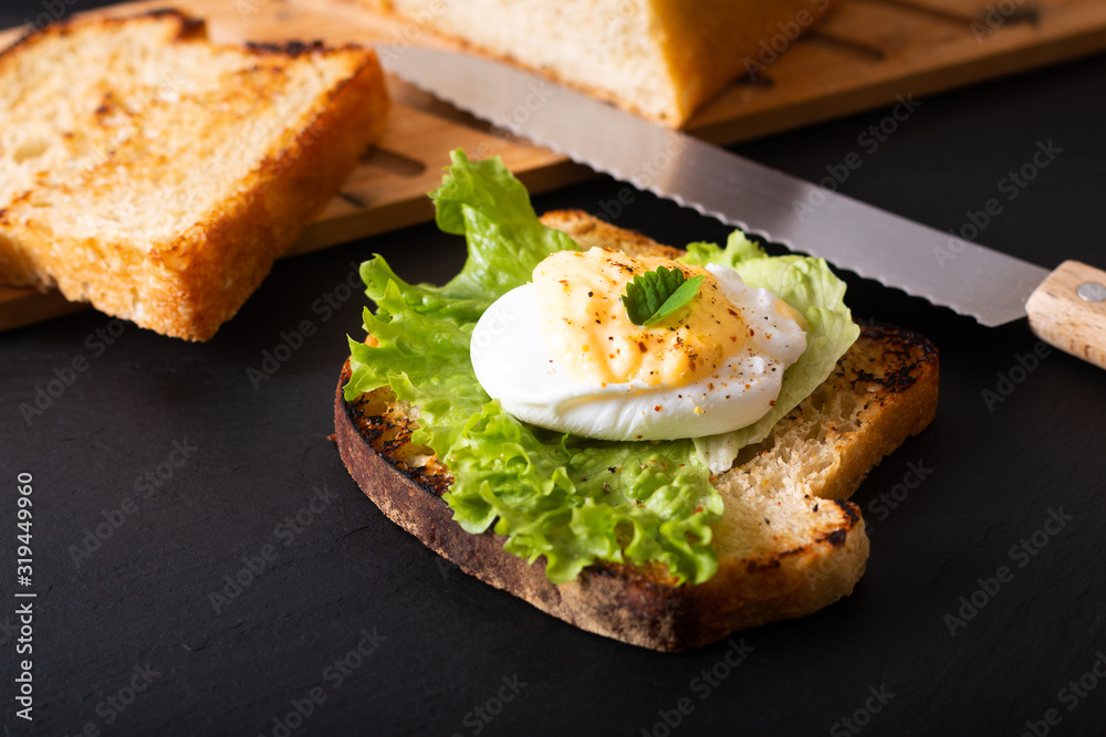 Organic Food breakfast concept homemade Poached egg or eggs benedict on sourdough bread toasted on black slate board Organic Food breakfast concept homemade Poached egg or eggs benedict on sourdough bread toasted on black slate board