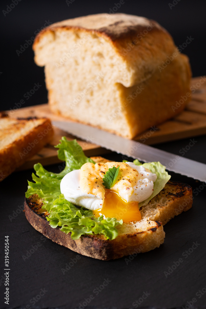 Organic Food breakfast concept homemade Poached egg or eggs benedict on sourdough bread toasted on black slate board