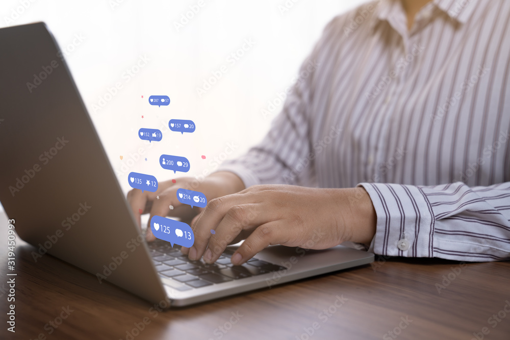 Person using a social media marketing concept on computer tablet with notification icons of like, chat, message and comment above tablet screen. Person using a social media marketing concept on computer tablet with notification icons of like, chat, message and comment above tablet screen.