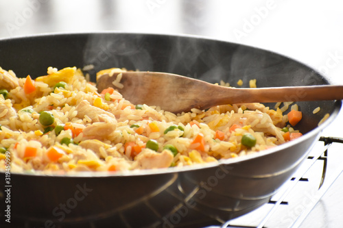 Chicken and egg fried rice with green peas and carrot in a frying pan. 