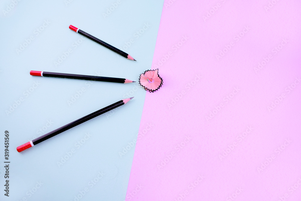 bunch of black sharpened pencils over a light blue background point at a pencil shaving which is over a pink background bunch of black sharpened pencils over a light blue background point at a pencil shaving which is over a pink background
