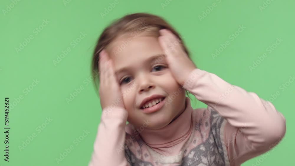 Video portrait of little surprised baby girl. Little happy female dressed in pink sweater looking at camera. Big eyes, white teeth and long brown hair. Stand on green isolated chroma key background Video portrait of little surprised baby girl. Little happy female dressed in pink sweater looking at camera. Big eyes, white teeth and long brown hair. Stand on green isolated chroma key background