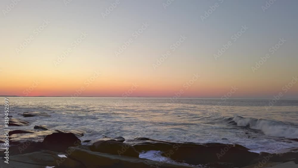 Blue sea waves glide over the rocks at sunset Blue sea waves glide over the rocks at sunset