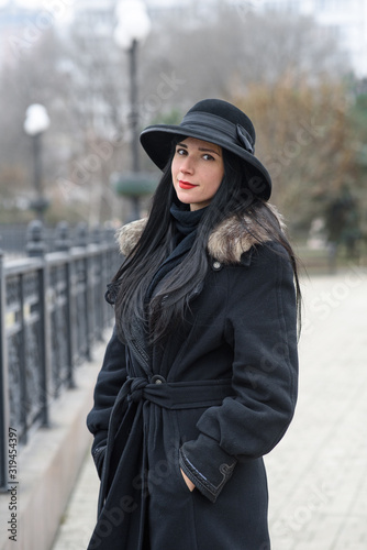 A nice girl in a beautiful gray coat and hat walks in the park on a cold autumn / winter day. Portrait photography.