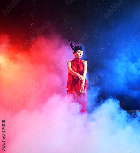 beautiful girl in clothes of the goddess of the earth in the rain in smoke on a black background