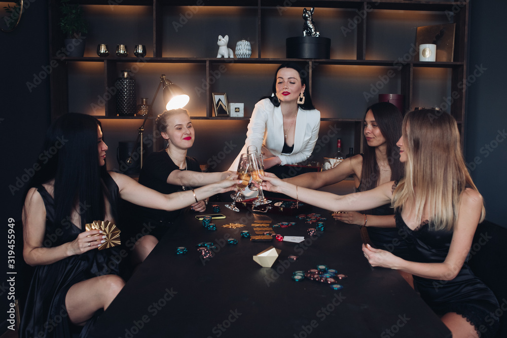 Group of fashion young sexy woman enjoying playing poker and drinking champagne medium long shot. Few glamour rich luxury female relaxing at casino drink alcohol beverage having party Group of fashion young sexy woman enjoying playing poker and drinking champagne medium long shot. Few glamour rich luxury female relaxing at casino drink alcohol beverage having party