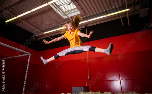 Happy fit child girl jumping on trampoline in fitness center