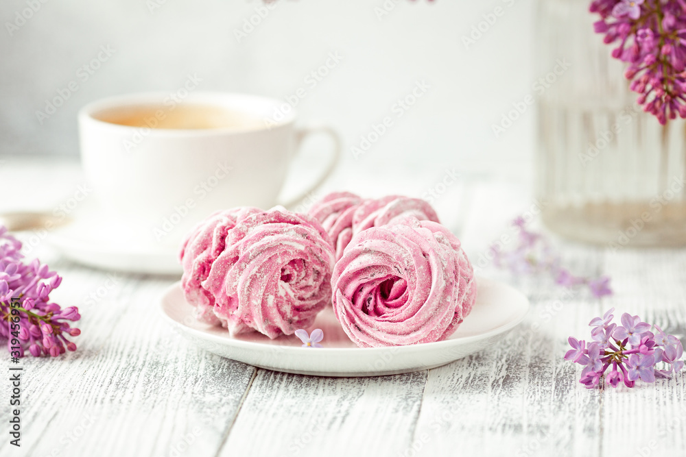 Lilac, coffee and homemade pink marshmallow on white ceramic plate. Romantic spring morning. Selective focus