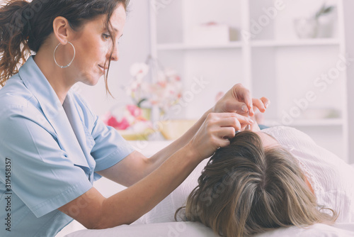 Therapist applying acupuncture needle photo