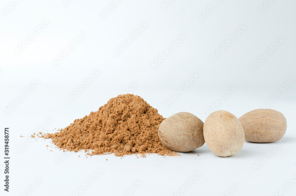 Nutmeg powder and whole nutmegs on the white background Nutmeg powder and whole nutmegs on the white background