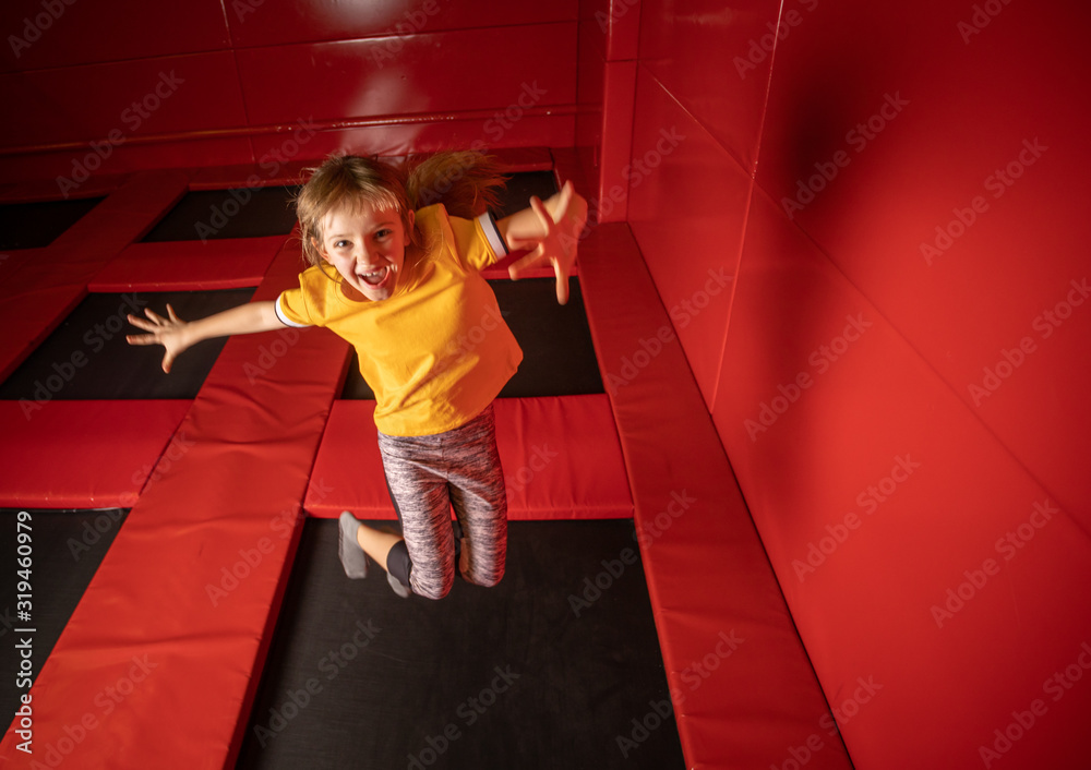 Little girl jumping on trampoline in fly park - obrazy, fototapety, plakaty 