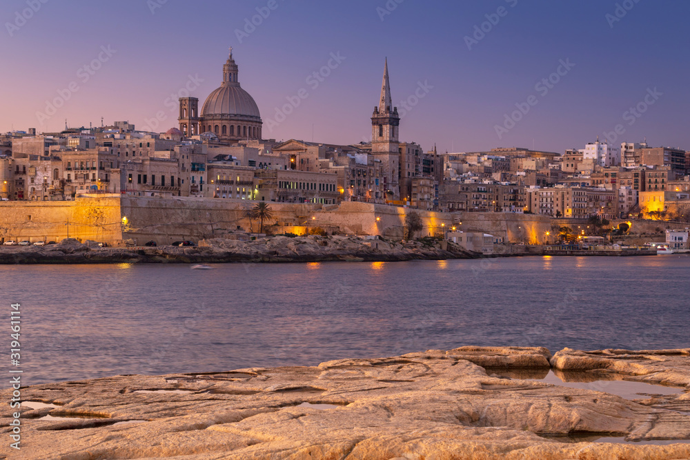 Obraz premium Rocky coastline of Malta and beautiful architecture of the Valletta city at dawn
