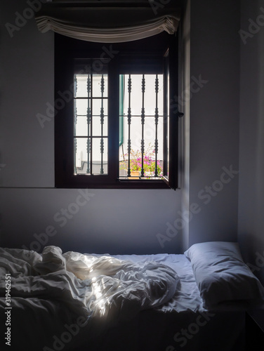 A room with a bed on which a ray of sun falls
